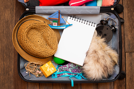 Packing a luggage for a new journey and travel for a long weekend on wooden table background