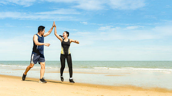 couple runners jump and touch hands And congratulate when able to practice according to the exercise program,Athletes practice running at the seaside And happy when successful in the training program