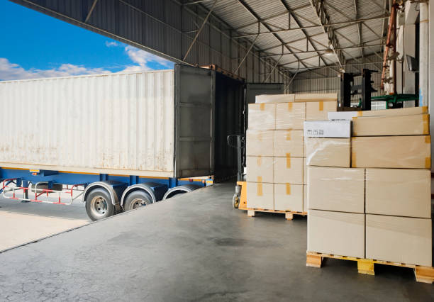 istock Road freight cargo shipment by truck. Large pallet goods waiting for load into caontainer truck at warehouse dock. 1248546291