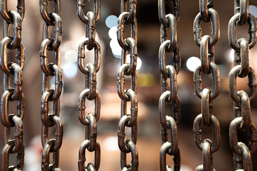 Iron chain hanging curtain or background wall which is use as decorating accessory for retro style building room. Selective focus at some point of chain element.