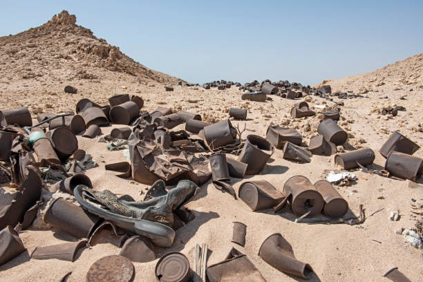 Closeup of tin cans rubbish pollution scattered and abandoned in remote arid desert landscape