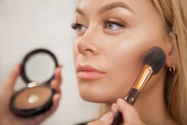 Gorgeous woman with professional makeup Close up of a beautiful woman getting glammed by professional makeup artist liquid foundation face stock pictures, royalty-free photos & images
