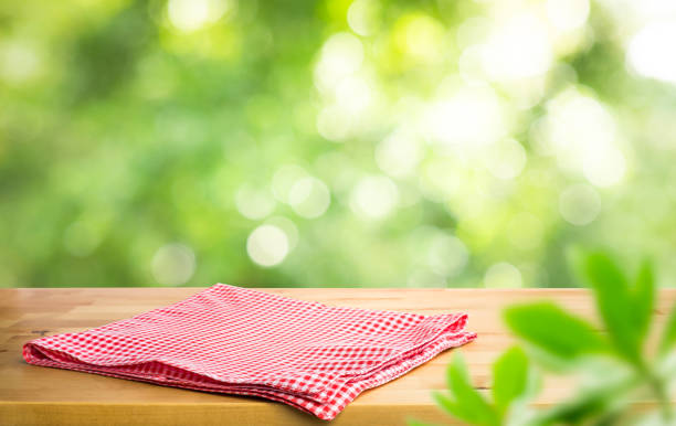 istock Red checked tablecloth on wood with blur green bokeh of tree background 1248554747