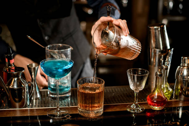 istock barman carefully pours drink from mixing cup into glass 1248555528