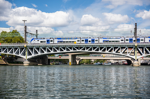 Regional express train near Perrache railroad station, on the riverbank of Saone river. This photo was taken during a sunny summer day from a small boat sailing on Saone river in the famous beautiful French city of Lyon, Rhone department in Auvergne-Rhone-Alpes region in France, Europe.