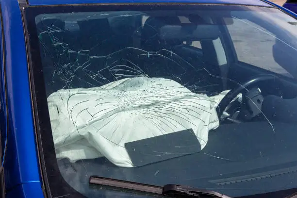 Broken car windshield and airbags deployed. The safety of modern cars. Glass broken by unfastened passenger seat belt