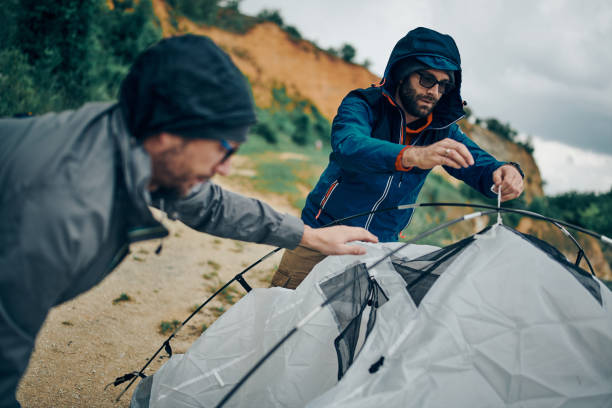 istock Two handsome men adjusting tent for camping in the mountains. 1248561209