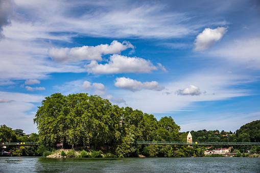 Beautiful island named Île Barbe with old church steeple on the riverbank of Saone river. Taken during a sunny summer day from a small boat sailing on Saone river, in the famous French city of Lyon, Rhone department in Auvergne-Rhone-Alpes region in France, Europe.