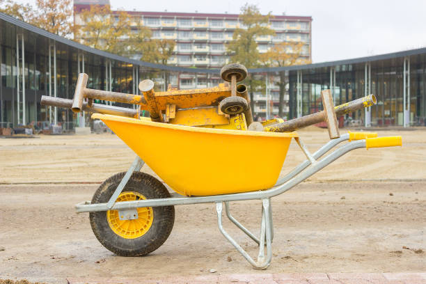 Yellow wheelbarrow with stone cutter on new square pavement. In the dutch shopping centre they made a circular shopping square. Because it's finished now, the wheelbarrow can transport the work tools.