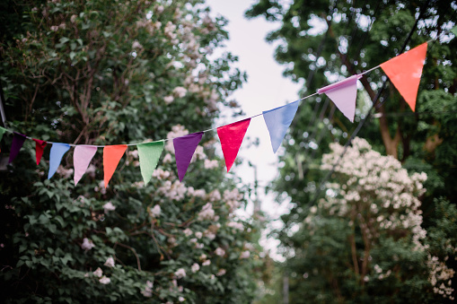 Colorful pennants hanging on a line between trees in the park as a decoration for a summer party in nature, copy space, selected focus