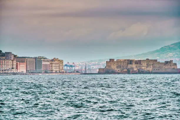 Looking over the Bay of Naples towards the Castel dell'Ovo wich is a seaside castle in Naples, located on the former island of Megaride, now a peninsula, on the Gulf of Naples in Italy. The Castel dell'Ovo is the oldest standing fortification in Naples.