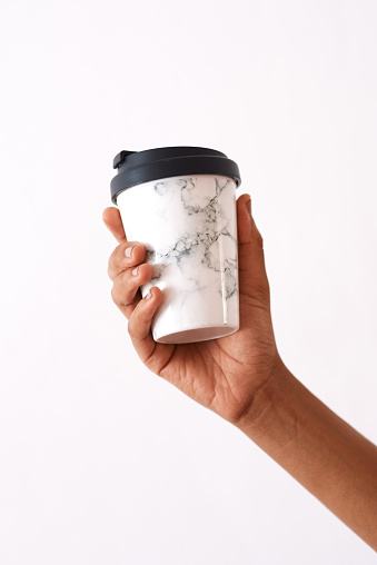 Studio shot of an unrecognizable woman holding a reusable coffee cup against a white background