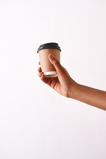 Studio shot of an unrecognizable woman holding a disposable coffee cup against a white background