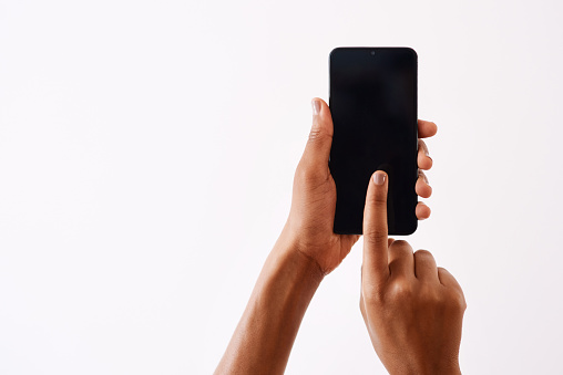 Studio shot of an unrecognizable woman holding a cellphone against a white background