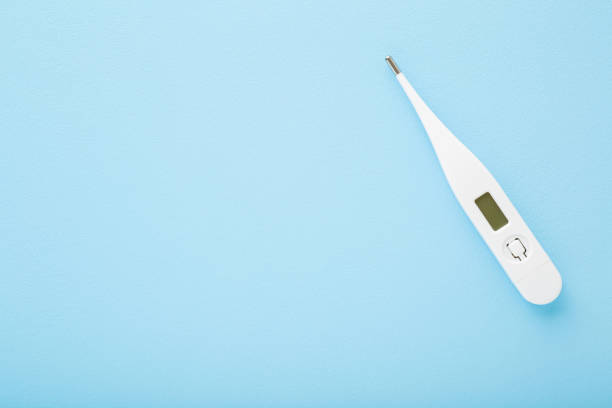 white digital thermometer on light blue table background. pastel color. fever and healthcare concept. closeup. empty place for text. top down view. - termómetro digital imagens e fotografias de stock