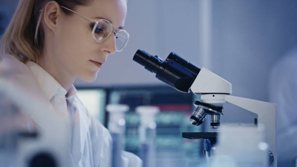 istock Attractive female microbiologist during research. Using microscope in futuristic lab 1248569395