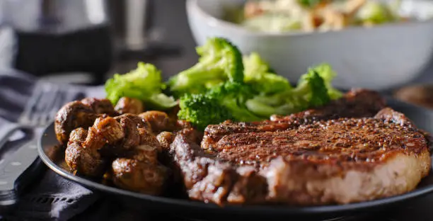 seared ribeye steak with broccoli and sauteed mushrooms in wide composition