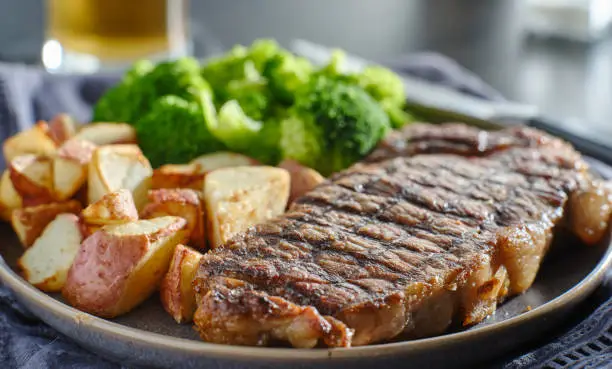 grilled new york steak with broccoli and roasted potatoes on plate