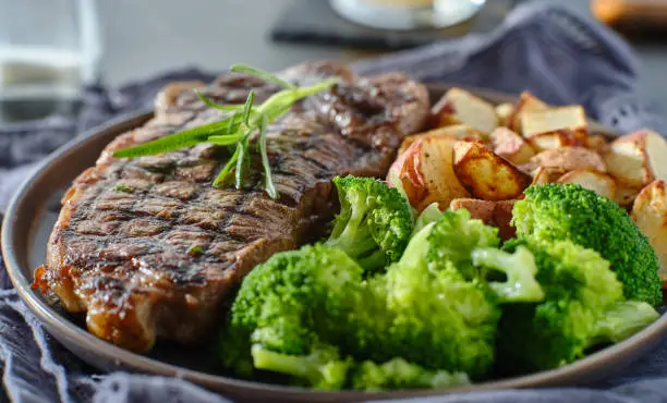 grilled new york strip steak with rosemary and vegetables on plate