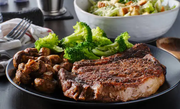 seared ribeye steak with broccoli and sauteed mushrooms on plate