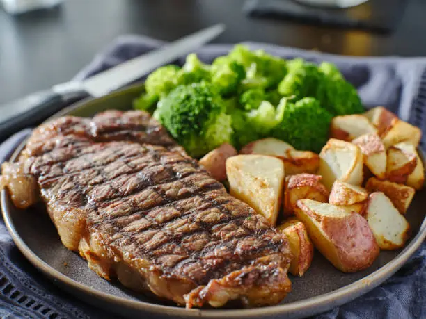 grilled new york steak with broccoli and roasted potatoes on plate