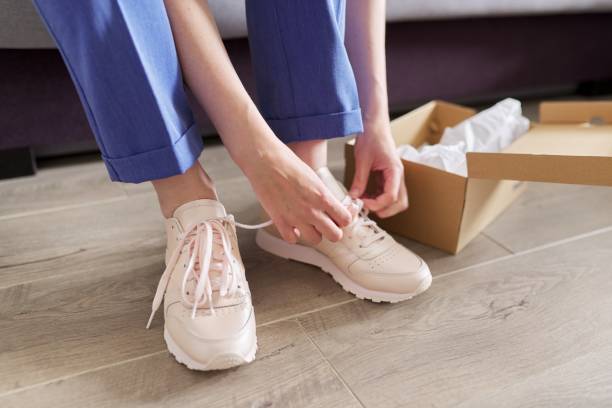 Close up of woman legs shoes new sneakers, box with sneakers at home background Close up of woman legs shoes new sneakers, box with sneakers at home background. woman legs open stock pictures, royalty-free photos & images