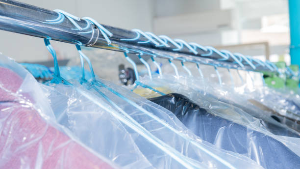 istock Clean clothes protected with plastic hanging on a rack in a professional laundry 1248571782