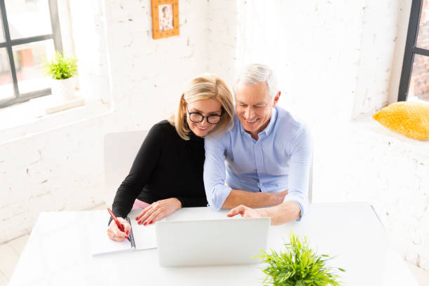 shot of a senior couple using a laptop together at home - home economics class imagens e fotografias de stock