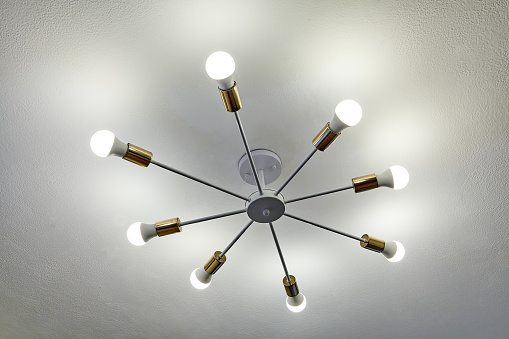 Aluminum ceiling chandelier with eight beams, at the end of which are of LED light bulbs. Economical home lighting.