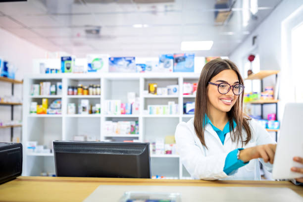 porträt einer engagierten apothekerin, die ein medikament aus dem regal nimmt, während sie brillen und labormantel während der arbeit in einem modernen drogeriemarkt mit verschiedenen pharmazeutischen produkten trägt - healthcare and medicine smiling group of people lab coat stock-fotos und bilder