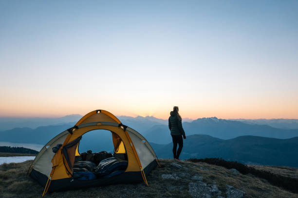 若い女性はキャンプテントの外で日の出を見ます - switzerland european alps ticino canton scenics ストックフォトと画像