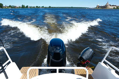 Boat in motion with of powerful engines at the stern and foam wake behind the stern of fast moving motor boat