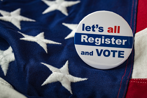 Photograph of register to vote button on American Flag.