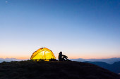junge frau beobachtet sonnenaufgang vor campingzelt