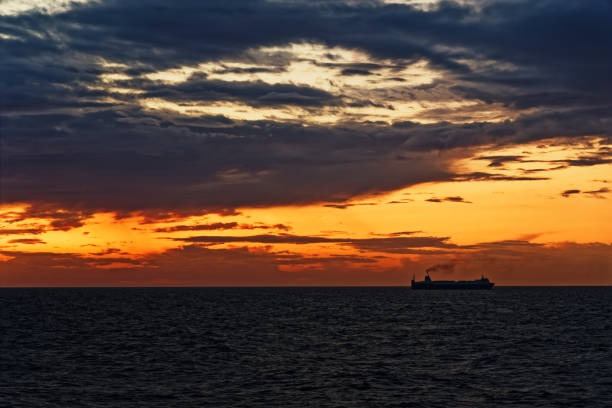 istock Colorful cloudy sky and ship silhouette at horizon during sunset 1248583772