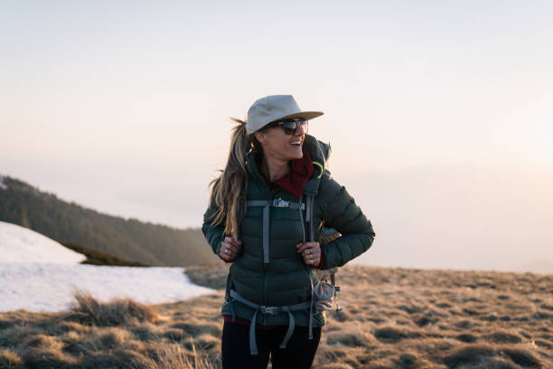 Young woman hikes across grassy mountain ridge