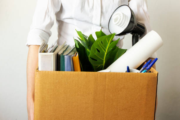 istock lose job concept. Hand holds box of fired worker. In a box they lay documents, folders, a flower, stationery, a table lamp. Unemployment concept 1248585452