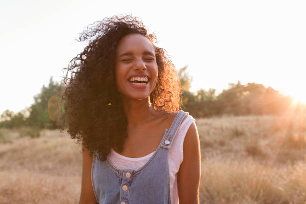 retrato al aire libre de una hermosa joven mujer afroamericana sonriendo al atardecer. fondo amarillo. modo de vida - women spring sensuality fashion model fotografías e imágenes de stock