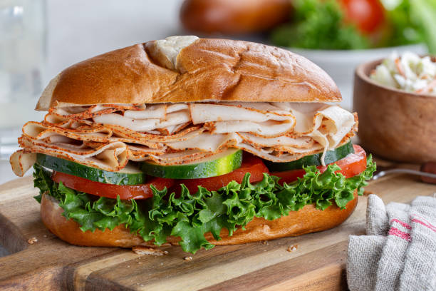 Turkey Submarine Sandwich Turkey submarine sandwich with cucumber. tomato and lettuce on a wooden cutting board cold cuts meat photos stock pictures, royalty-free photos & images