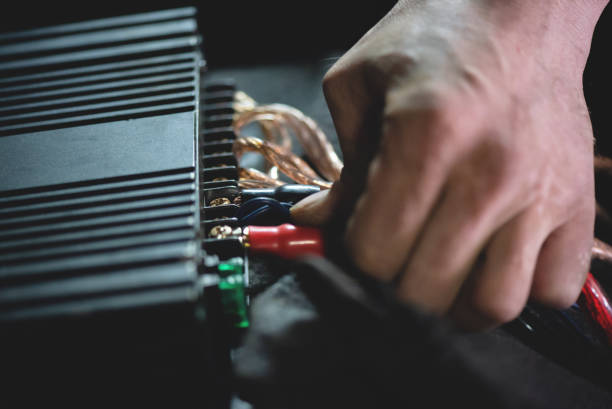 Car audio. Auto electrician is connecting a wiring to car amplifier close up. amplifier photos stock pictures, royalty-free photos & images