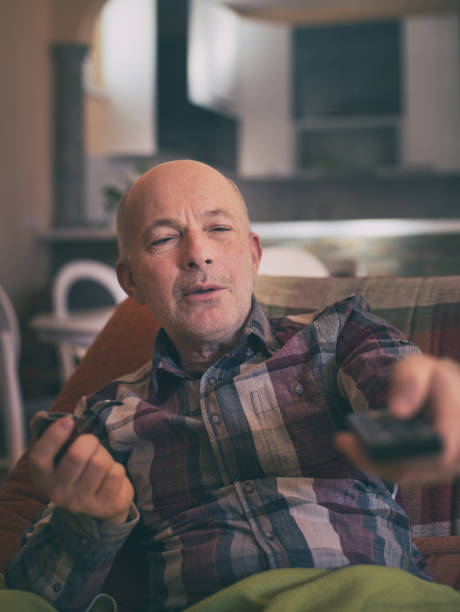 istock Old man smoking pipe and watching tv 1248592628