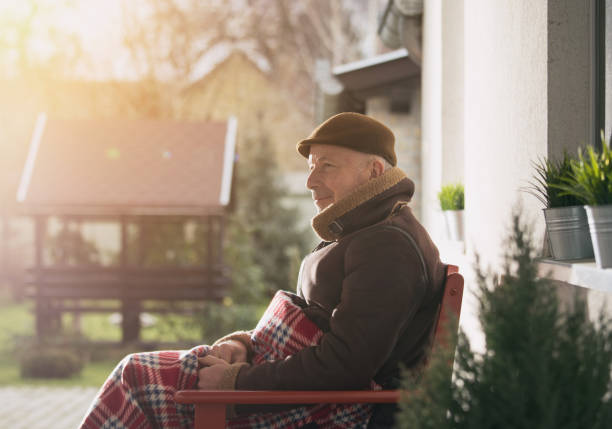 Man sitting on porch covered with blanket