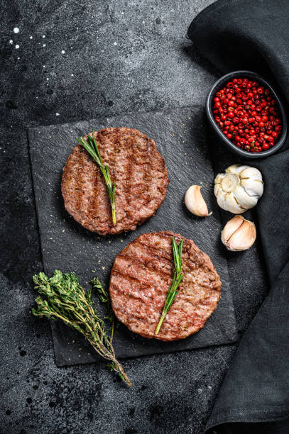 istock Grilled ground beef patties. BBQ meat. Black background. Top view 1248597576