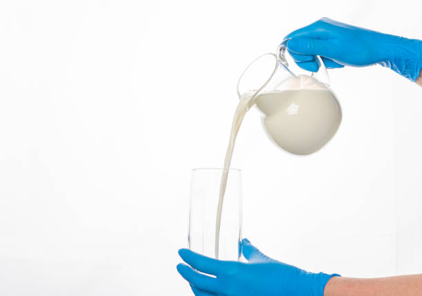 istock hands in protective gloves pour milk from a decanter into a glass on a white background 1248600349