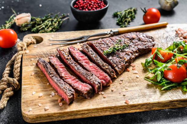 grilled rump steak with spices on a chopping board. barbecue beef. black background. top view. - flank steak imagens e fotografias de stock