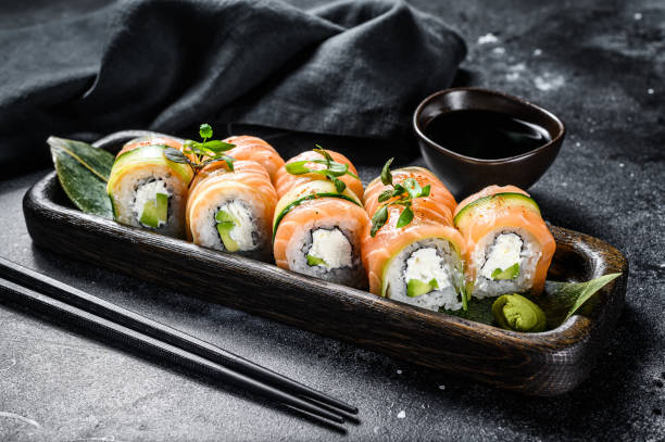 sushi roll philadelphia con salmone, avocado, crema di formaggio. menu sushi. cibo giapponese. sfondo nero. vista dall'alto - sushi foto e immagini stock