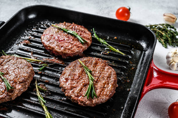 Beef burger patties sizzling on a hot barbecue pan. White background. Top view Beef burger patties sizzling on a hot barbecue pan. White background. Top view. ground beef photos stock pictures, royalty-free photos & images