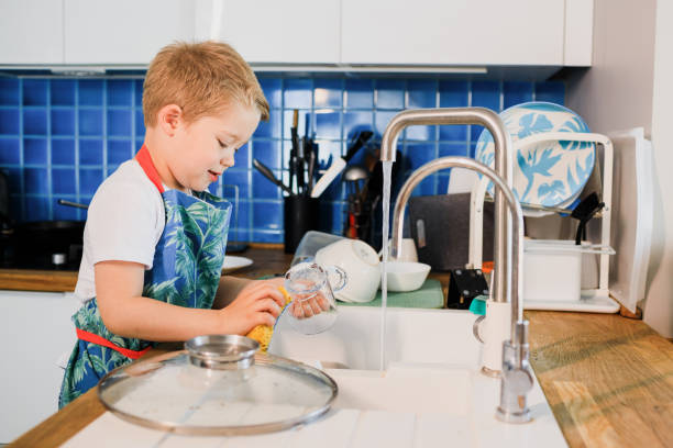 istock a boy in an apron washes dishes in the kitchen at home 1248604823