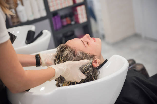 young teenage girl washing her hair in a hair salon, reopening business after coronavirus, covid-19 quarantine - hair color dyed hair hair dye human hair imagens e fotografias de stock