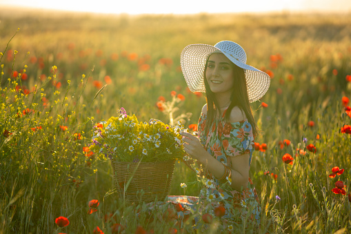 Young female beauty in the white fields of red poppy
